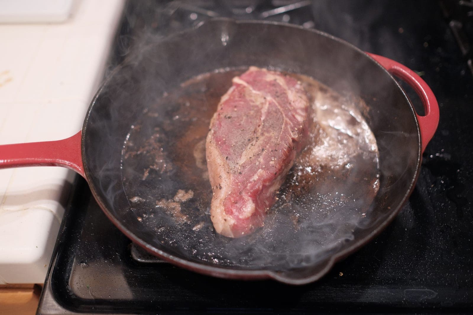 Food searing in a well-seasoned cast iron skillet on a stovetop