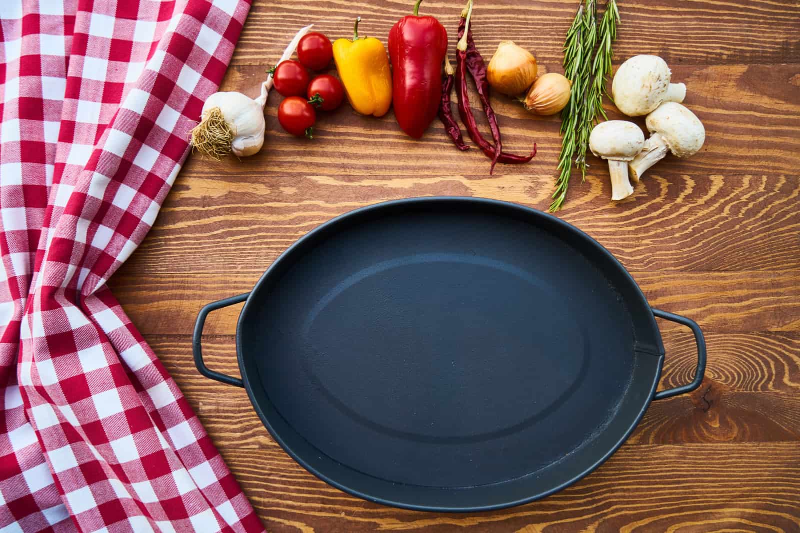 Cast iron pans side by side on a warm wooden board